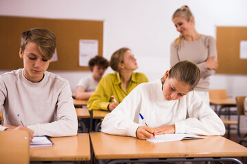 Portrait of teenage school girl and boy sitting together in classroom during lesson in secondary school