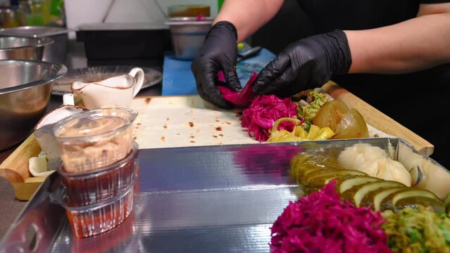 Chef in kitchen of restaurant collects assortment of pita bread with pickles, cabbage, garlic, restaurant menu Assorted pickled or pickled vegetables. Sauce