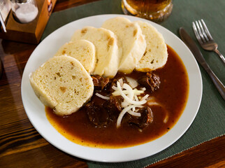 Tasty dumplings (knedliky) served in Prague pub with beef stewed in gravy. Traditional Czech dish