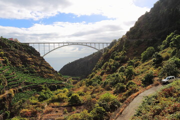 Wild landscape with a car in the foreground and a bridge in the background