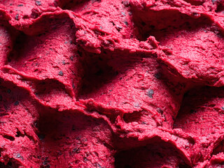 Frozen Black Currant flavour gelato - full frame detail of sorbet. Close up of a red surface texture of Ice cream filled with pieces of mixed fruit.