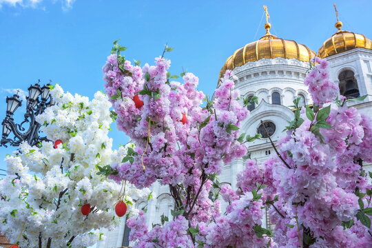 Easter composition of white and pink flowers, Easter eggs on the background of domes and crosses