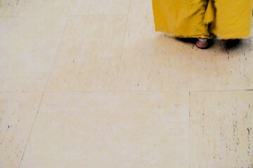 Abstraktes Motiv mit barfuß auf weißem Boden stehender Tänzerin mit weiter gelber Hose 