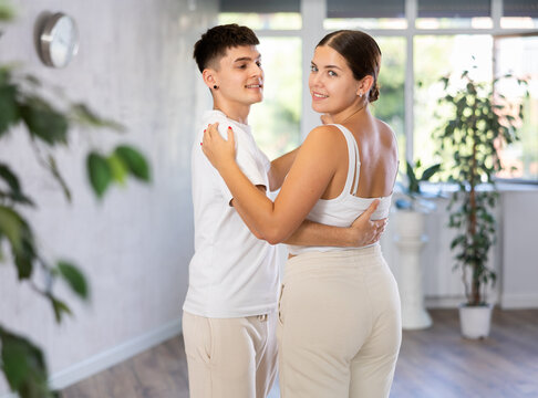 Guy and girl are standing next to each other and dancing in pair of salsa. Teenagers practice repeating movements of pair dance