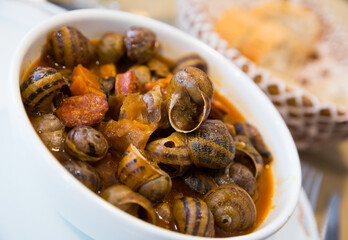 Fototapeta premium Homemade gourmet food. Delicious stewed escargots with chorizo sausages ..