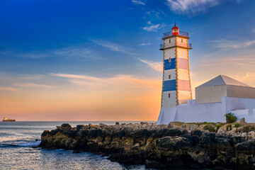 Fototapeta na wymiar Colorful sunset on sea shore and Santa Marta lighthouse in Cascais