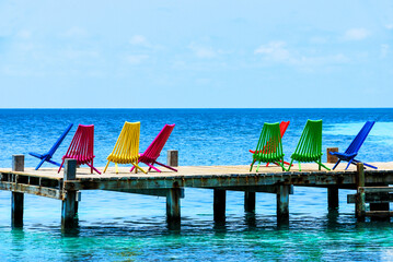 Multicolored Adirondack Chairs on a pier, overlooking the Ocean, Belize, Caribbean
