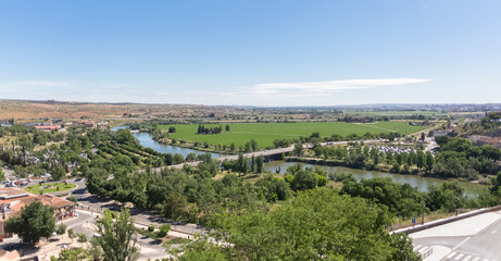 Fototapeta na wymiar amic aerial view of the outskirts of the city of Toledo, parks with trees, Tagus river or Tejo river, agricultural fields and horizon, in Spain