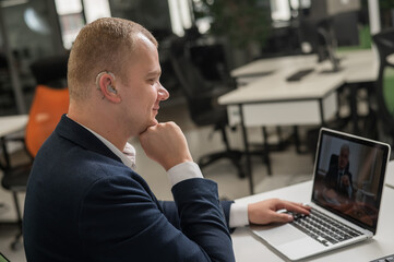 Caucasian man with hearing aid at online meeting on laptop. 