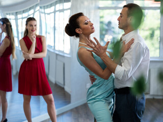 Female coach and man student perform passionate tango dance and teach master class of classical...
