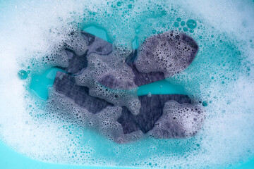 Dirty socks soaked in water, dissolving detergent in basin.