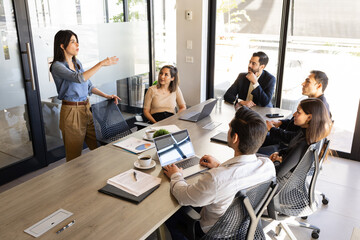 Female boss and team leader sharing some ideas with a group of people in a meeting room
