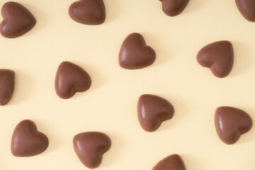 Creative love pattern composition made with chocolate hearts on light beige background. Minimal love concept. Trendy chocolate hearts idea. Chocolate aesthetic. Romantic flat lay.