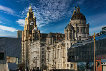 Liverpool's iconic waterfront buildings under a blue sky with wispy clouds.