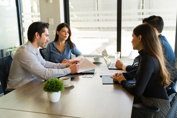 Young couple buying a house and signing a contract in a meeting room