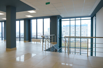 An empty spacious room of a modern office building with large windows. An empty hall with columns...