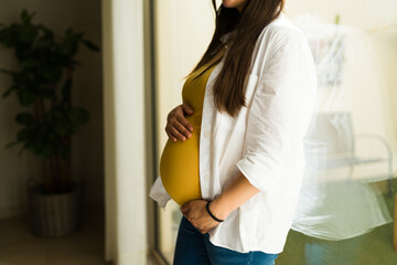 Maternal pregnant woman touching her big belly