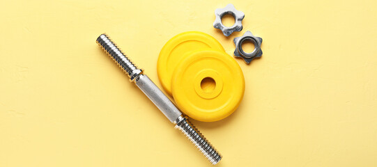 Barbell plates, clamps and grip on yellow background