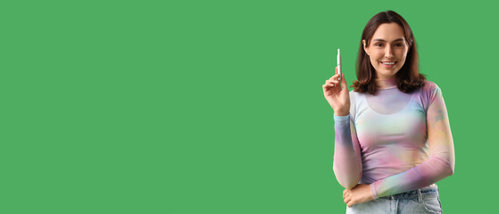 Young woman with electronic cigar on green background