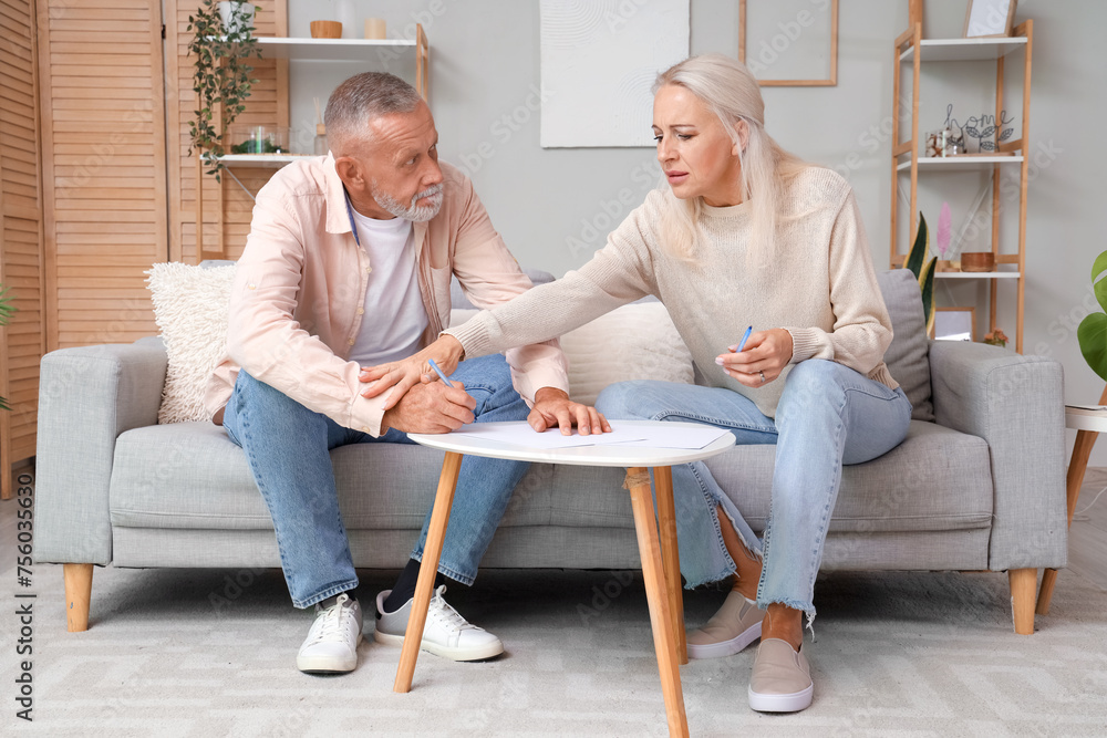 Wall mural Mature couple signing divorce decree at home