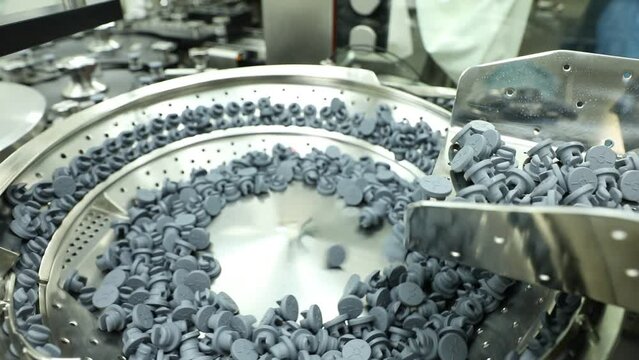 Bottle stopper rubber vial bottle caps in a creative shot vial caps moving in a machine in a pharmaceutical factory. side view of a lot of pharma products moving into a hi tech machine equipment