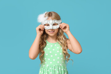 Adorable little girl wearing carnival mask on blue background