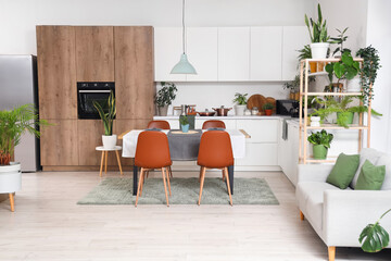 Interior of modern kitchen with green plants, dining table and counters