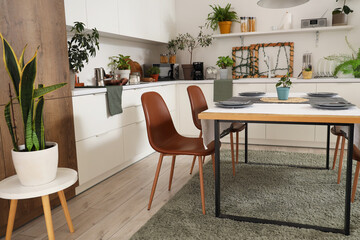 Interior of modern kitchen with green plants, dining table and counters