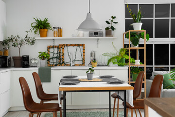 Interior of modern kitchen with green plants, dining table and counters