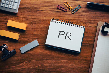 There is notebook with the word PR. It is an abbreviation for public relations as eye-catching image.