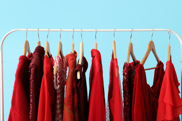 Rack with stylish clothes on blue background