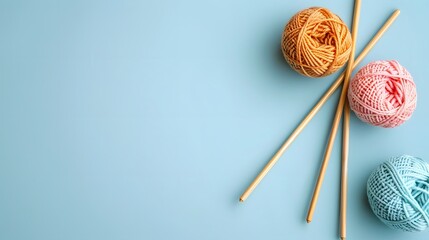 Three balls of thread and wooden bamboo knitting needles on light blue background. Hobby,...