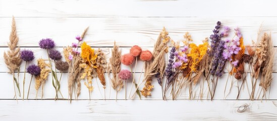 Artfully arranged, a row of dried flowers adorns a white wooden table, creating a picturesque scene...
