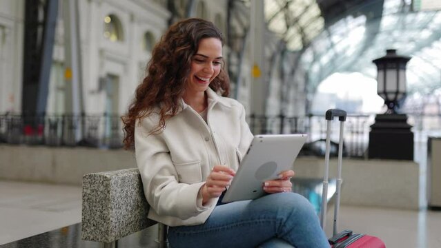 Young adult business woman using digital tablet waiting the train at station. Travel and business lifestyle concept