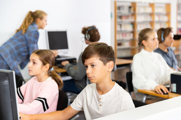 Group of youth boys and girls using computers in library.