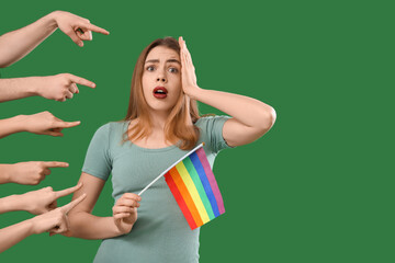 People pointing at shocked young woman with LGBT flag on green background. Accusation concept