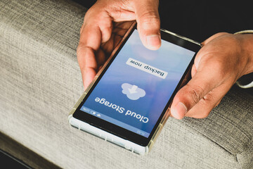 Person using online file sharing storage service to upload and backup his personal data on the mobile device.
