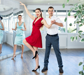 Couple learns dancing during individual lesson in classical and modern dance studio. Young girl...