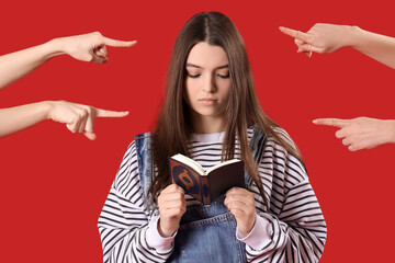 People pointing at young woman with Koran on red background. Accusation concept