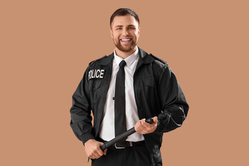 Male police officer with baton on beige background