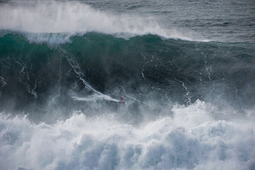 big wave surfer in giant wave at Nazaré Praia do Norte