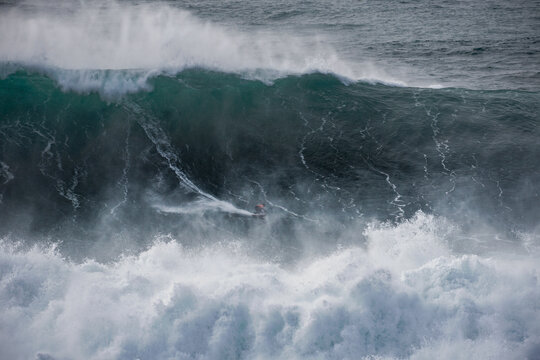 big wave surfer in giant wave at Nazar&eacute; Praia do Norte