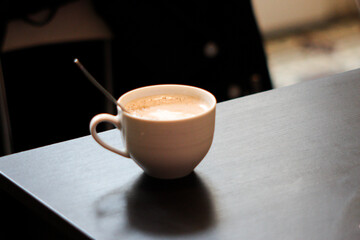 Cup of coffee or chai with spoon on table