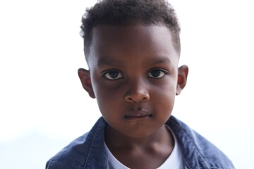 Mixed race African and Asian boy is playing at the outdoor area. smiling happy boy has fun running on the beach. portrait of boy lifestyle with a unique hairstyle.