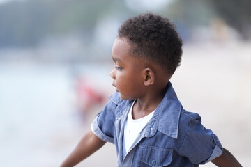 Mixed race African and Asian boy is playing at the outdoor area. smiling happy boy has fun running on the beach. portrait of boy lifestyle with a unique hairstyle.