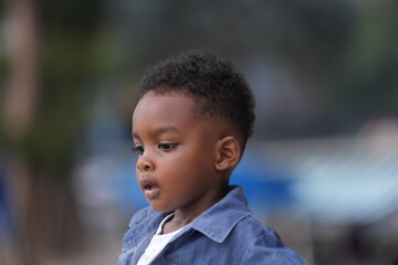 Mixed race African and Asian boy is playing at the outdoor area. smiling happy boy has fun running on the beach. portrait of boy lifestyle with a unique hairstyle.