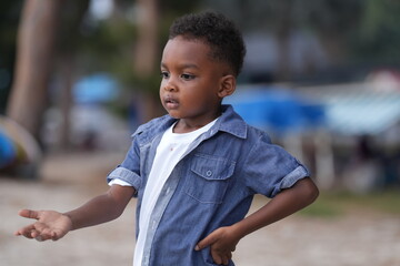 Mixed race African and Asian boy is playing at the outdoor area. smiling happy boy has fun running on the beach. portrait of boy lifestyle with a unique hairstyle.