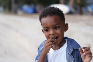 Mixed race African and Asian boy is playing at the outdoor area. smiling happy boy has fun running on the beach. portrait of boy lifestyle with a unique hairstyle.