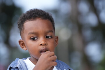 Mixed race African and Asian boy is playing at the outdoor area. smiling happy boy has fun running on the beach. portrait of boy lifestyle with a unique hairstyle.