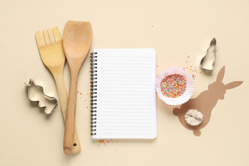 Blank notepad for recipes with Easter bunny, colorful sprinkles and kitchen tools on beige...